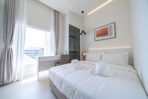 Et moderne hotelværelse med en stor seng, et skrivebord og udsigt over byen.