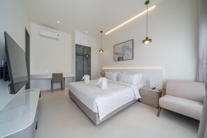 Una habitación de hotel moderna con una cama grande, televisor, escritorio y sofá.