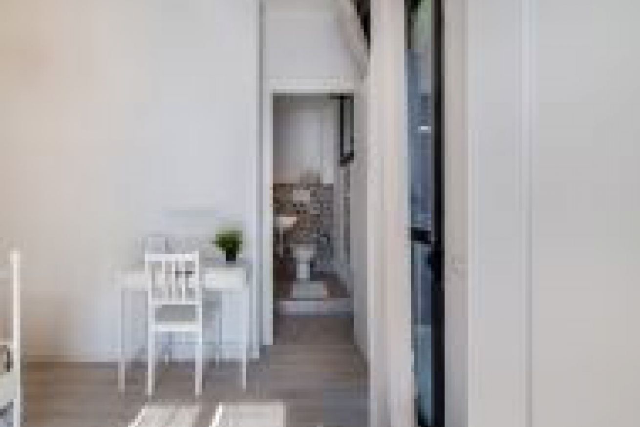 A modern interior with a dining area featuring a white table and chairs, a small plant, and a view into a kitchen area.
