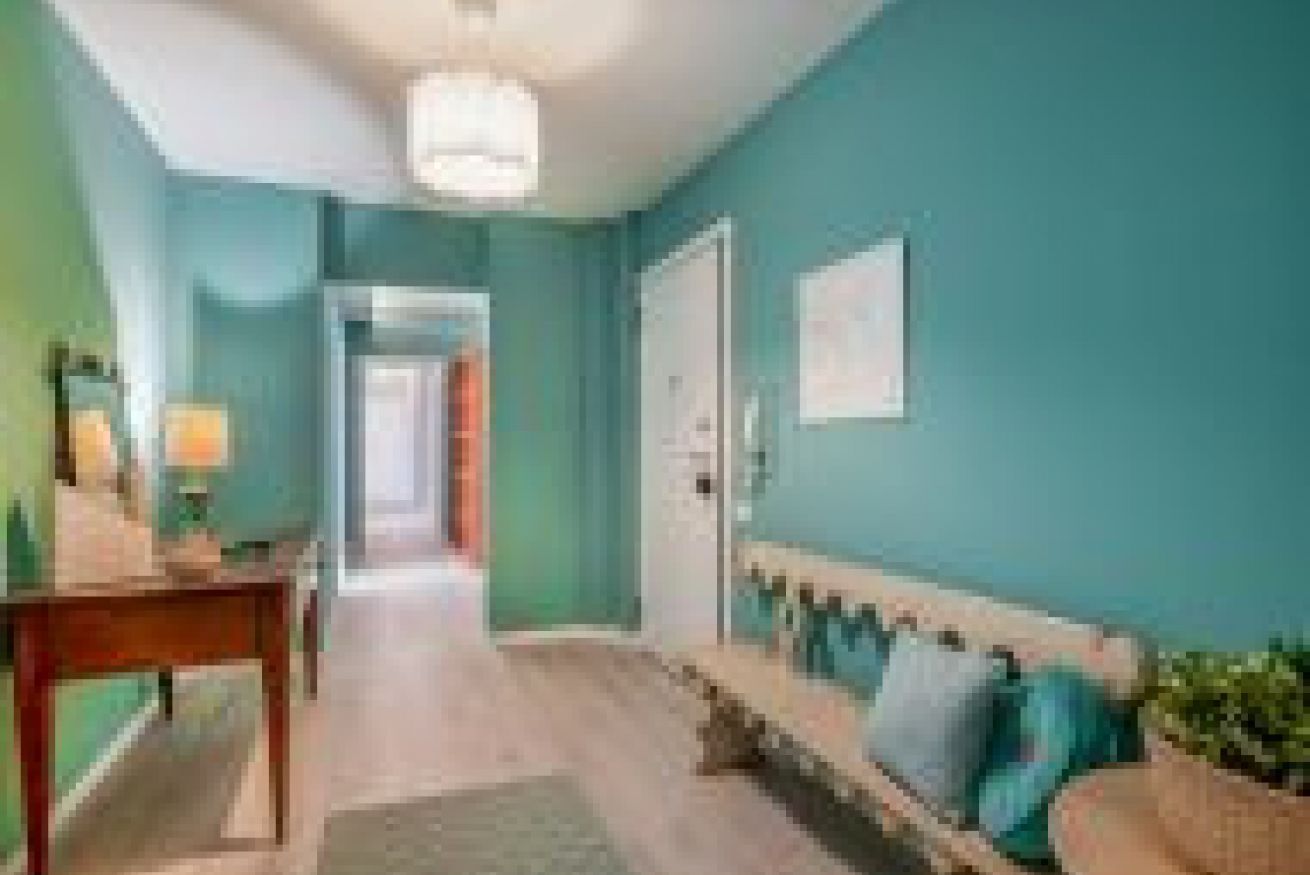 A hallway with a wooden bench, a door, and a wall-mounted picture.
