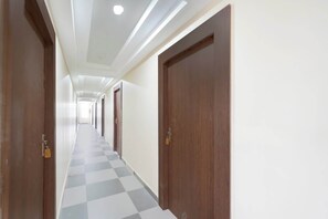 Un largo pasillo con piso a cuadros, puertas de madera e iluminación empotrada.