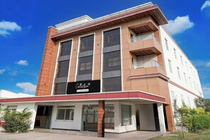 Um edifício de vários andares com uma placa grande chamativa com a palavra 'Collection', janelas amplas e um telhado plano.
