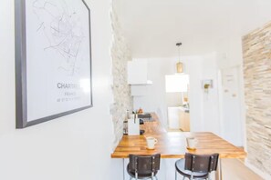 A modern kitchen with a wooden countertop, two chairs, and a hanging light fixture. - Appartement le Off (Chartres)