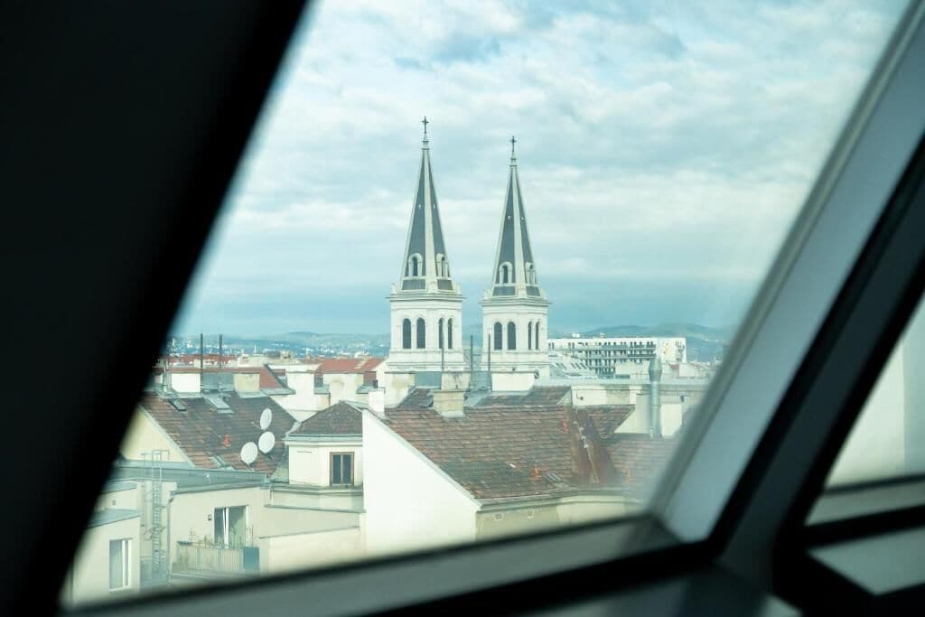 A view of a church with two spires from inside a vehicle.