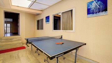 A ping pong table with wheels, a red carpet, and a painting of a snowy landscape on the wall.