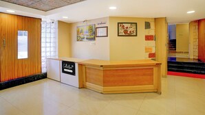 A reception desk with a wooden finish, a 'No Smoking' sign, and a painting on the wall. - Collection O Gold Valley (Lonavala)