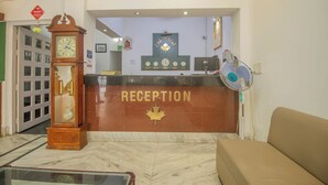 A reception area with a clock, a maple leaf emblem, and a fan. - Collection O Sevoke Crossway Siliguri (Siliguri)
