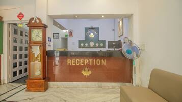 Un área de recepción con un reloj, un emblema de hoja de arce y un ventilador.