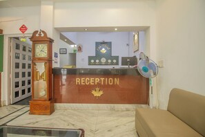 Un área de recepción con un reloj, un emblema de hoja de arce y un ventilador.