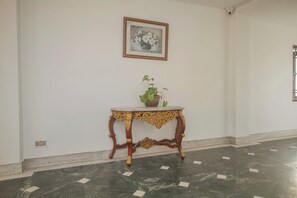 A room with a marble floor, a decorative table with a plant, and a framed picture on the wall. - Collection O Sevoke Crossway Siliguri (Siliguri)