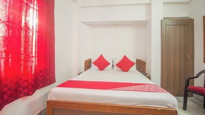 A hotel room with a bed, a chair, a wardrobe, and a red curtain. - Collection O Sevoke Crossway Siliguri (Siliguri)
