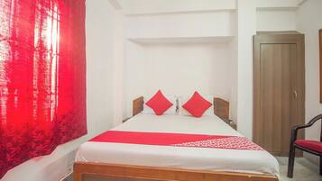 Habitación de hotel con cama, una silla, armario y una cortina roja.