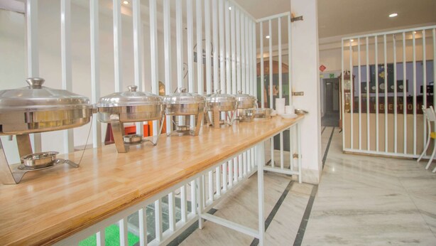 A buffet setup with multiple food service stations, a wooden counter, and a white railing. - Collection O Sevoke Crossway Siliguri (Siliguri)