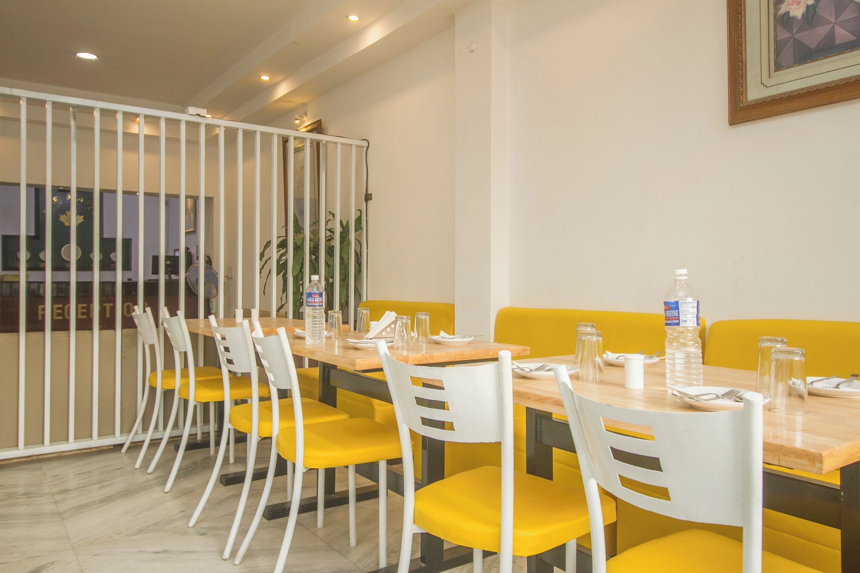 A conference room with a long table, yellow chairs, white chairs, and a white partition.