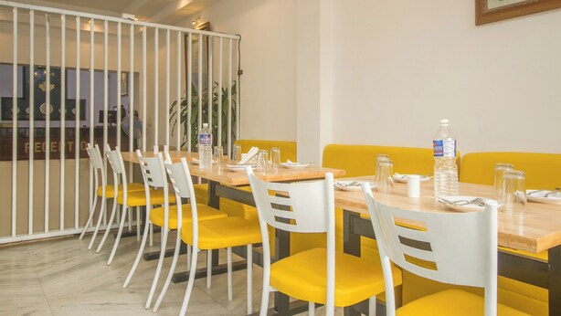 A conference room with a long table, yellow chairs, white chairs, and a white partition. - Collection O Sevoke Crossway Siliguri (Siliguri)