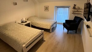 Ett sovrum med två sängar, en stol, ett skrivbord och ett fönster.