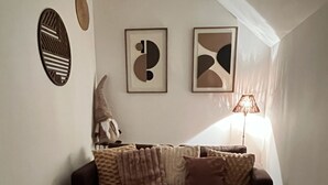 Ett vardagsrum med en soffa i mörk färg, en rund matta och två abstrakta konstverk på väggen.