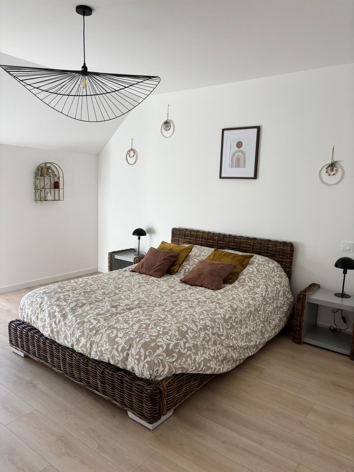 Ein Schlafzimmer mit einem großen Bett, einer Hängeleuchte, einem kleinen Nachttisch und einem an der Wand hängenden Bild.
