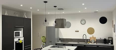 A modern kitchen with a central island, black cabinetry, and stainless steel appliances.