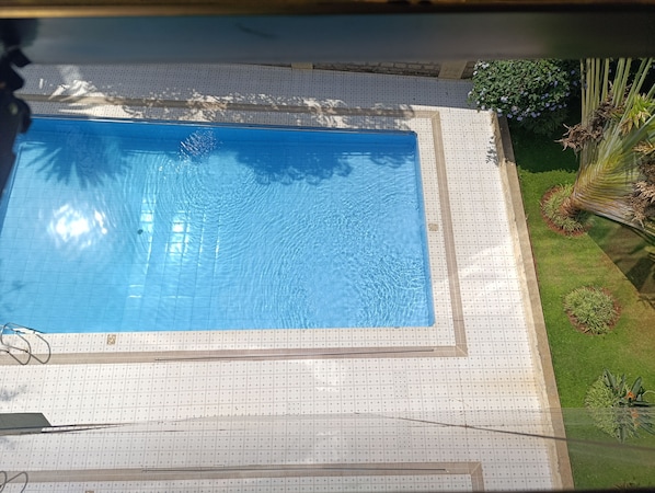 Una piscina rectangular con un solárium de diseño cuadriculado a su alrededor.