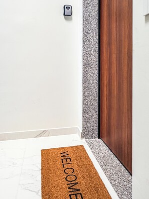 Ein Flur mit Fußmatte, einer Tür und einem wandmontierten Gerät.
