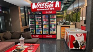 Zona de Coca-Cola con máquinas expendedoras, un sofá y una mesa con material promocional.