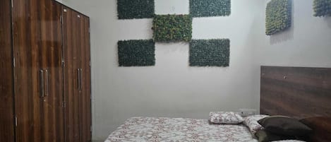 A bedroom with a bed, a wardrobe, and a wall with a geometric pattern.