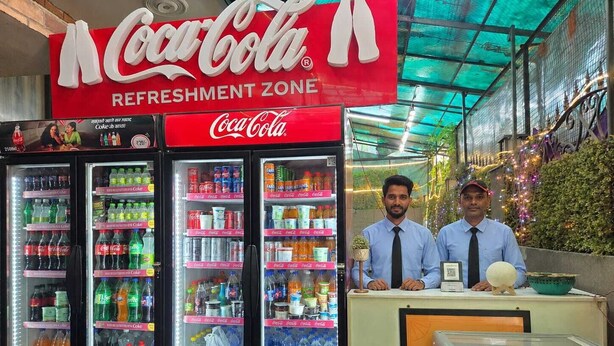 Zona de refrigerio con Coca-Cola y máquinas expendedoras llenas de diversas bebidas.