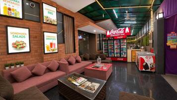 Un espacio lounge moderno con sofá, mesa de centro y menús enmarcados que ofrecen comida y bebidas.