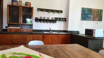 A kitchen with wooden cabinets, a sink, a microwave, and a painting on the wall.