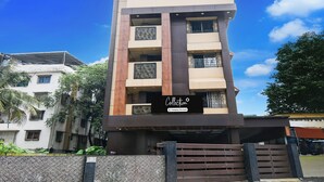 A multi-story building with a modern architectural design, featuring a prominent entrance with a sign. - Collection O New Jalpaiguri Railway (Jalpaiguri)