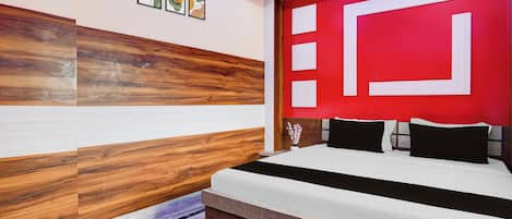 A modern bedroom with a bed, a red accent wall, and wooden paneling.