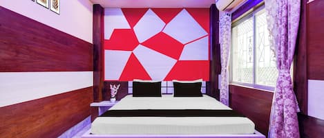 Un dormitorio moderno con un diseño geométrico en la pared, una cama con ropa de cama blanca y negra, y una ventana con cortinas moradas.