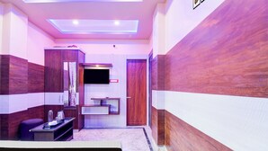 A hotel room with a bed, a desk, a mirror, a wardrobe, and a door. - Collection O New Jalpaiguri Railway (Jalpaiguri)