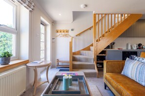 A modern living room with a staircase, a dining area, and a kitchen. - Idyllic 1BDR Cottage on the Edge of Edinburgh (Edinburgh)
