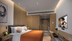 Een moderne hotelkamer met een bed, een bureau, een stoel, een televisie en een badkamer.