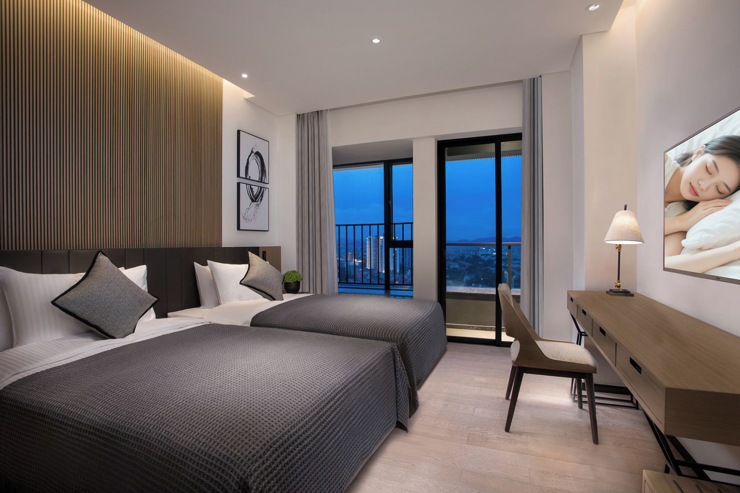A hotel room with two beds, a desk, a chair, and a large window with a city view.