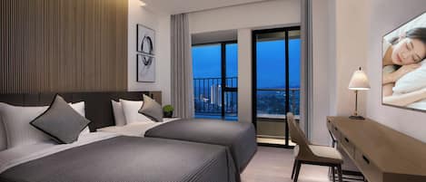 A hotel room with two beds, a desk, a chair, and a large window with a city view.