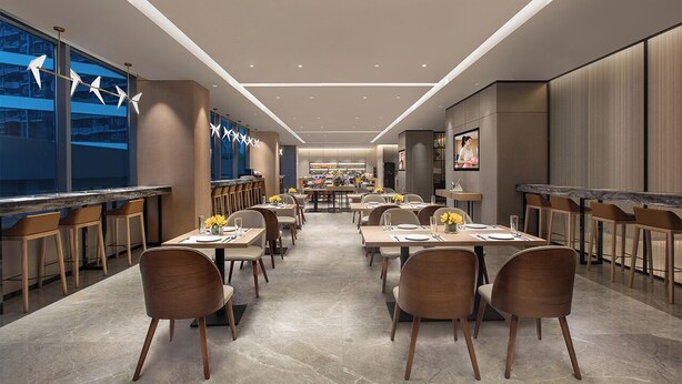 Een modern restaurant met een lange toonbank, verschillende eettafels en stoelen.