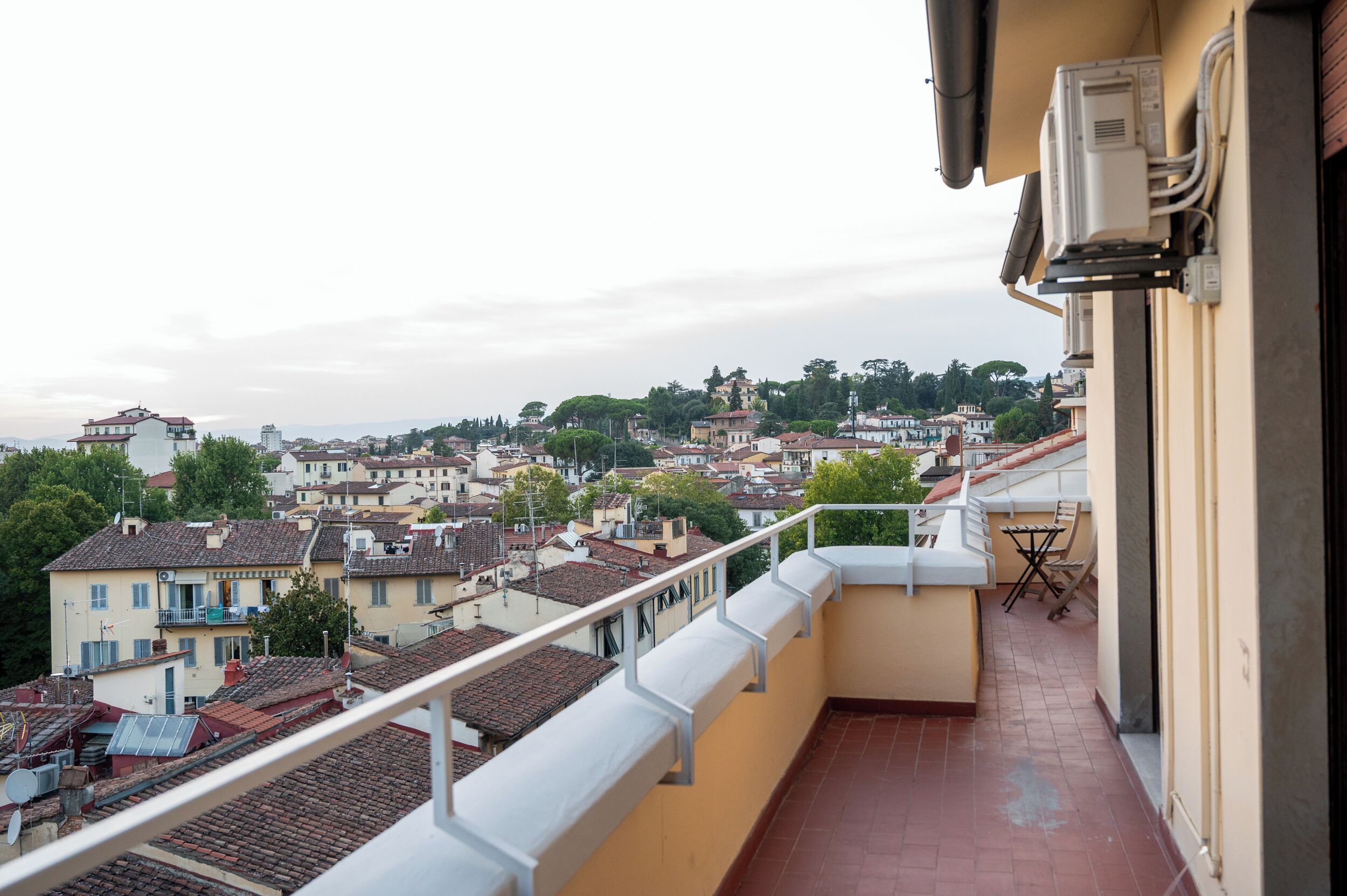 Un balcón con vista a una zona residencial, con casas y árboles.