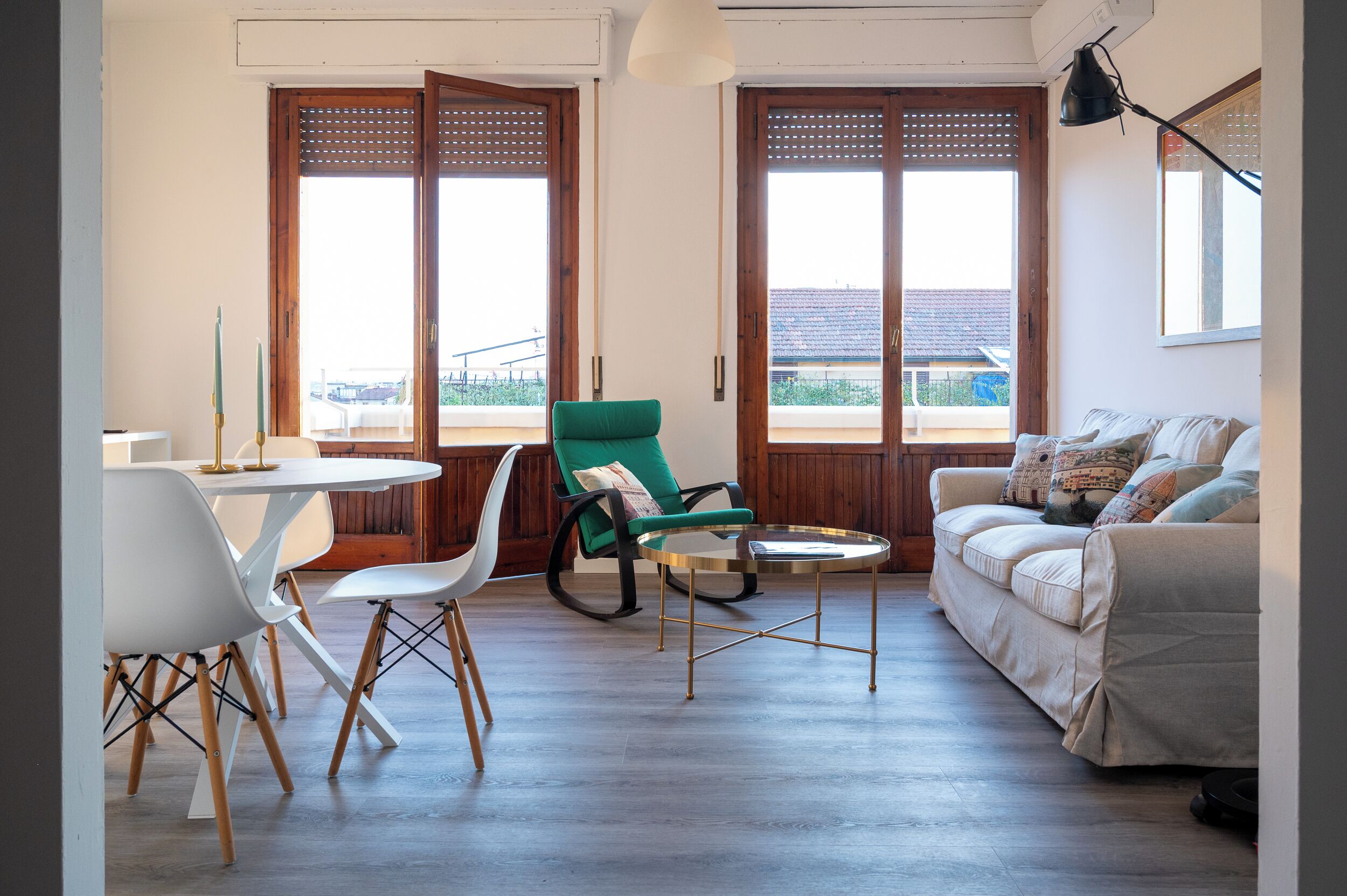 Una sala de estar con un sofá, una mesa de comedor con sillas y un sillón verde.