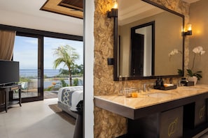 A modern bathroom with a large mirror, marble countertop, and a view of the ocean. - The Sankara Hill Penida (Penida Island)