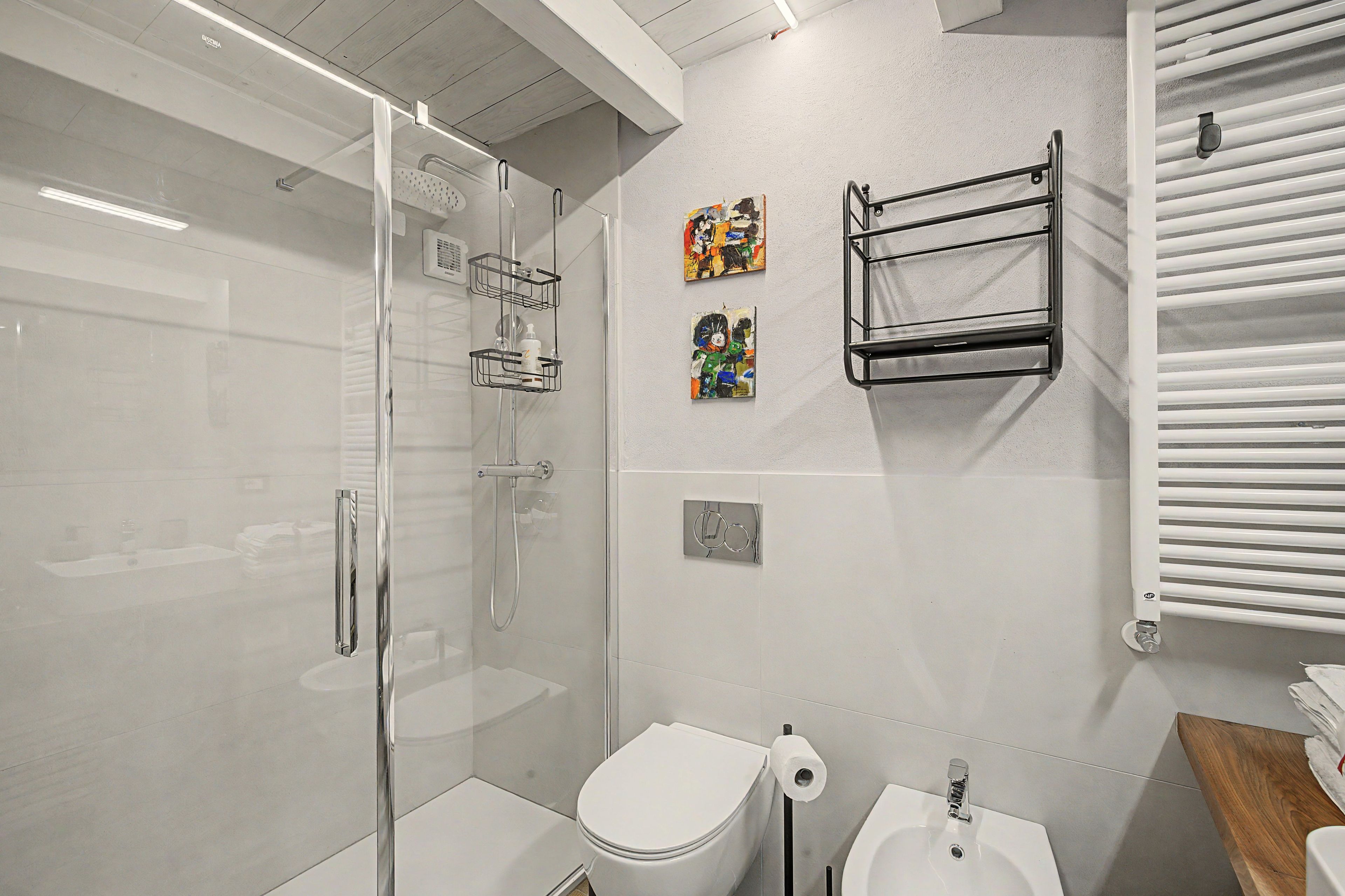Ein modernes Badezimmer mit einer Duschkabine, Toilette, Bidet und Handtuchhalter.