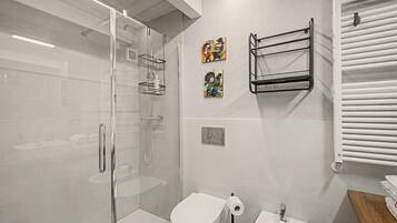 Ein modernes Badezimmer mit einer Duschkabine, Toilette, Bidet und Handtuchhalter.