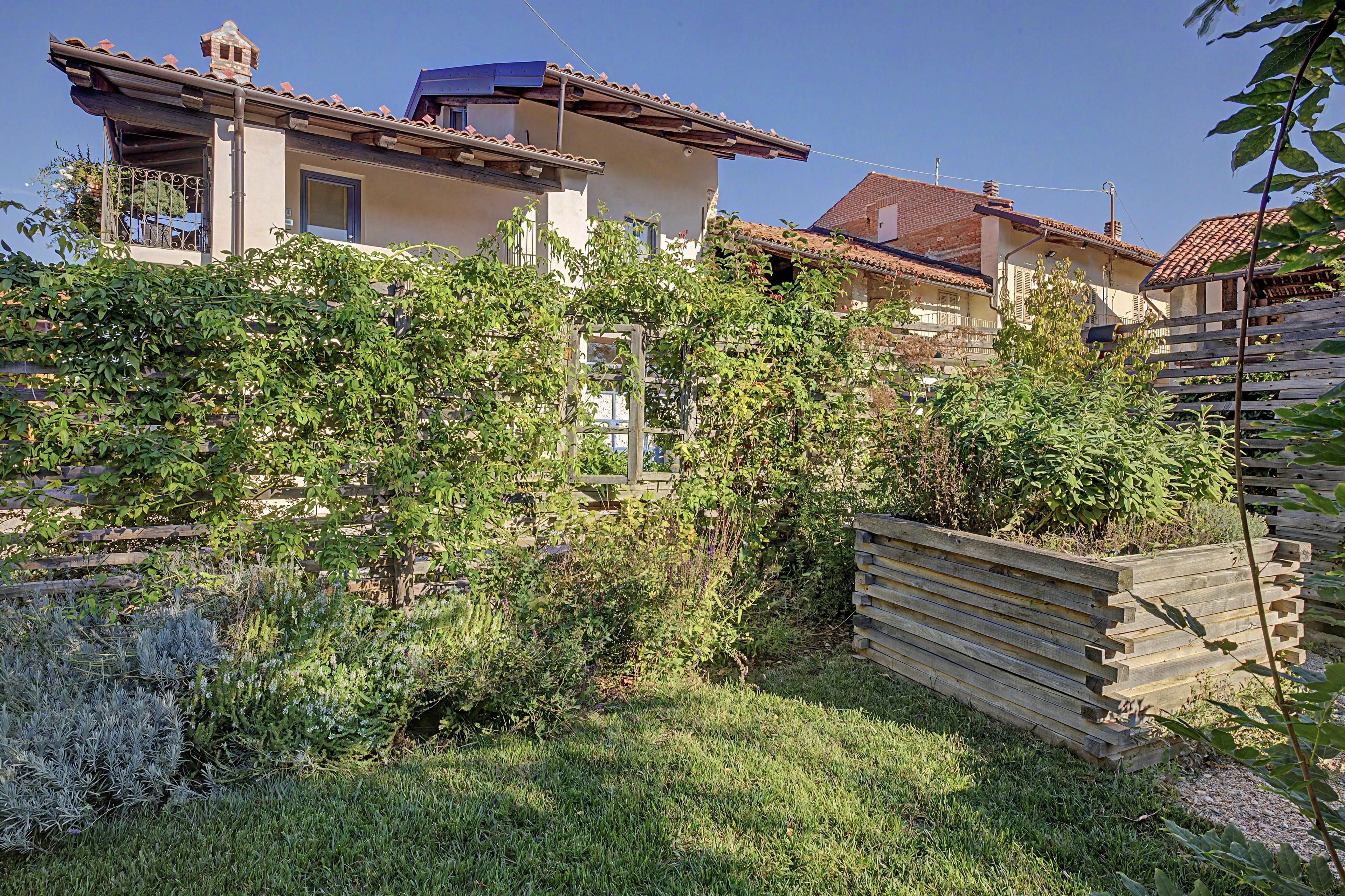 Un quartiere residenziale con case, una recinzione in legno e vegetazione rigogliosa.