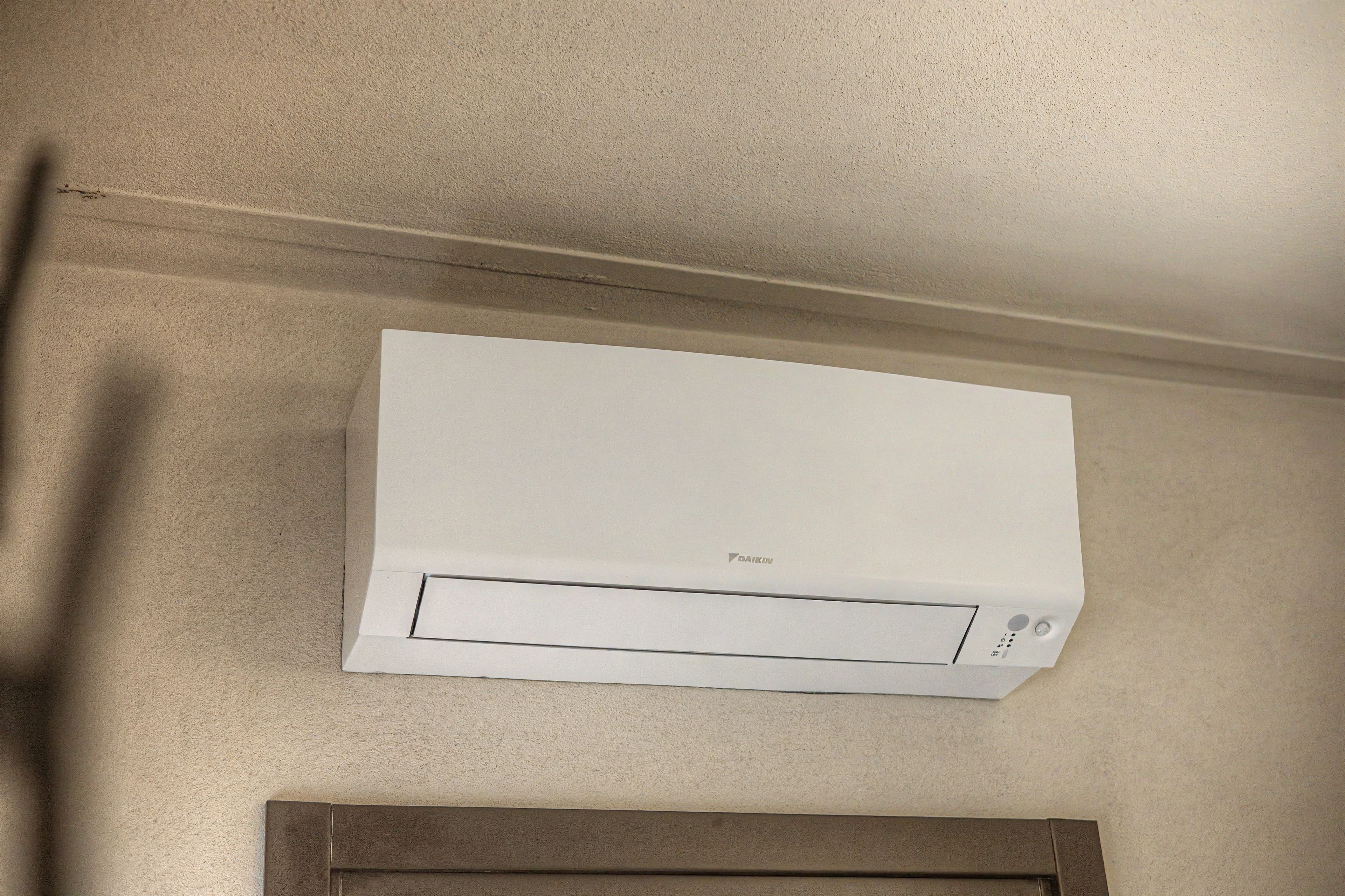 A white air conditioning unit mounted on a wall with a visible brand logo.