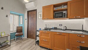 A compact kitchen with wooden cabinets, a microwave, a kettle, and a small sink. - Accessible "Terre" Apartment near Garden with Wi-Fi and Air Conditioning (Dogliani)