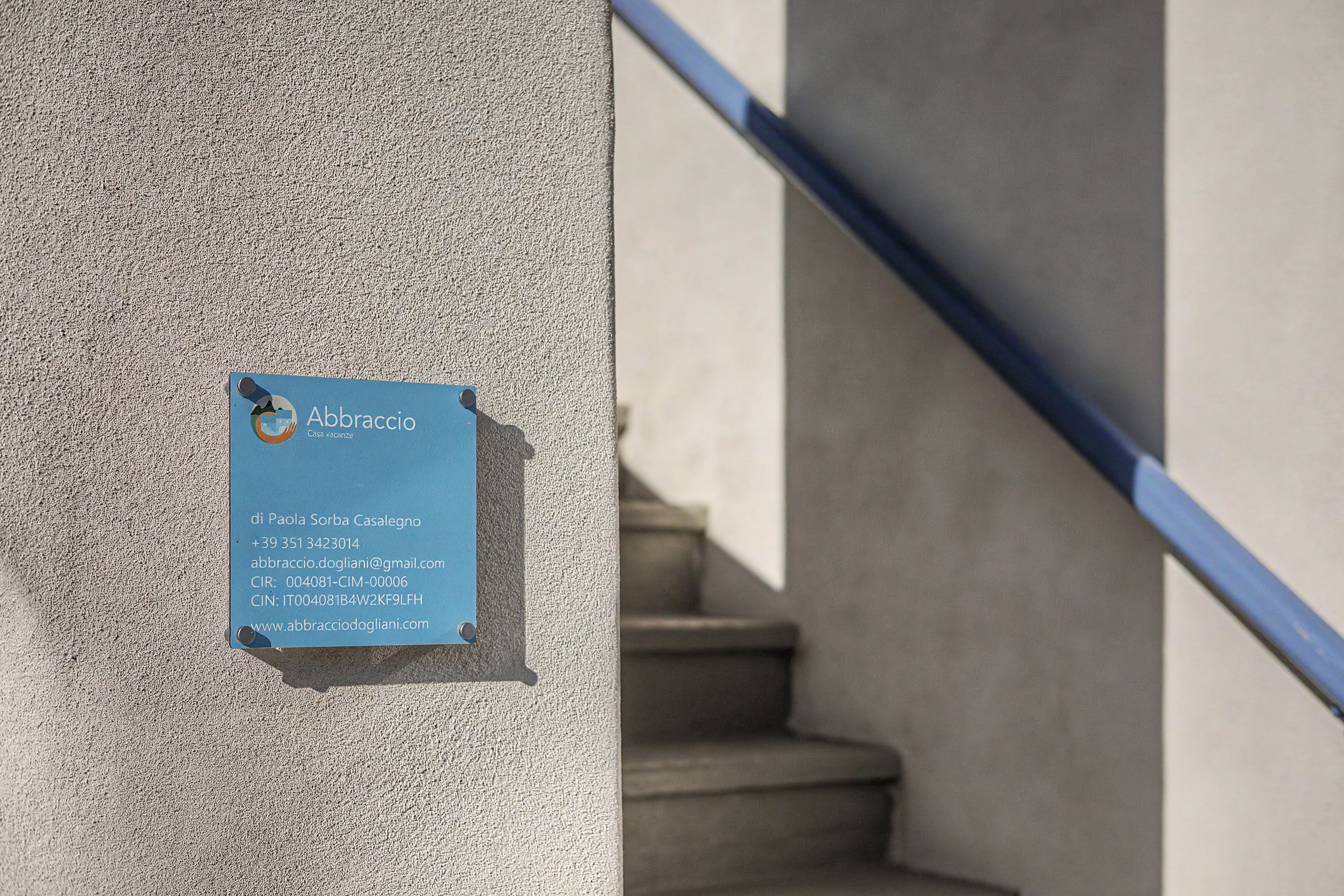 Ein blaues Schild mit Kontaktinformationen für ein Anwesen namens 'Abbraccio'.