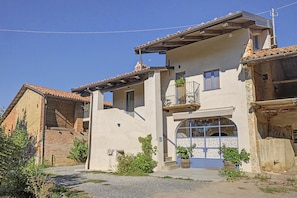 A two-story building with a balcony, a large arched window, and a gravel driveway.