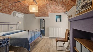 A room with a bed, a chair, a radiator, and a ceiling with exposed brick. - Accessible "Terre" Apartment near Garden with Wi-Fi and Air Conditioning (Dogliani)